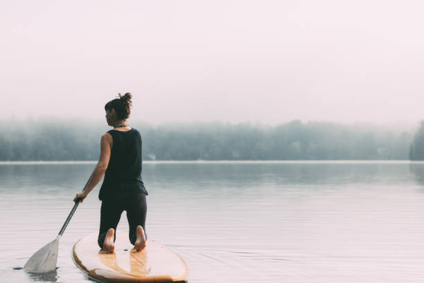Young woman stand-up paddle on a quite Canadian lake. La Mauricie, Québec, Canada