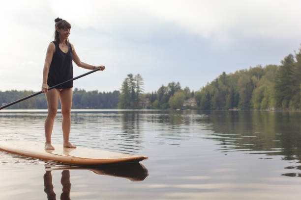 istock Young Woman Paddleboarding On A Calm Lake 1211629232