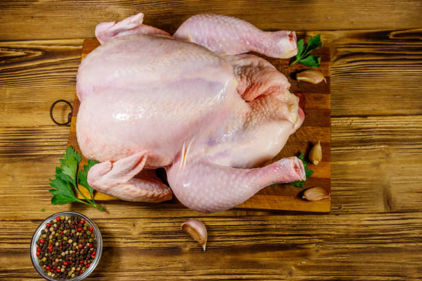 istock Raw whole chicken with spices on a wooden table. Top view 1211629247