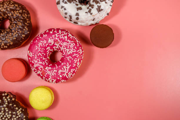 istock Tasty donuts and macaroons on pink background. Top view, copy space 1211629255