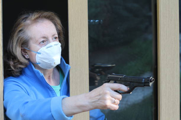 istock Senior woman wearing protective mask holding a weapon 1211633146
