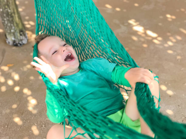 Toddler swinging on a hammock at the beach in Macapá, Piauí, Brazil. Laughing out loud having a good time.