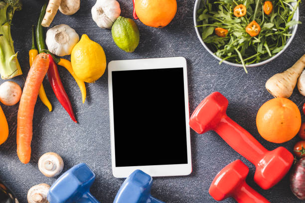 Digital tablet, dumbbells, vegetable and fruit Digital tablet, dumbbells, vegetable and fruit on dark background Barbell stock pictures, royalty-free photos & images