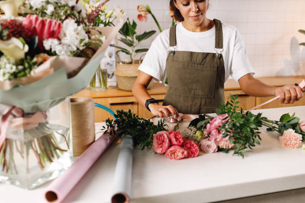istock Female florist creating a bouquet with ribbon at table 1211636127