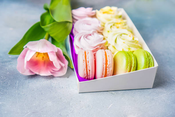 istock Box with macaroon and marshmallow cakes on the table. Tulip lying near the box with sweets. Copy space. 1211639808