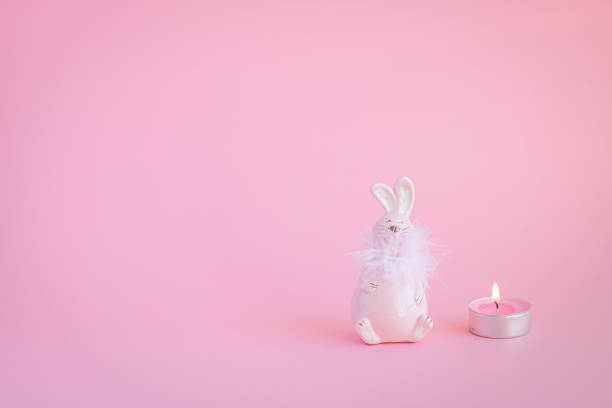 Bunny and candle on the pink background with copy space. Minimalistic Holidays concept.
