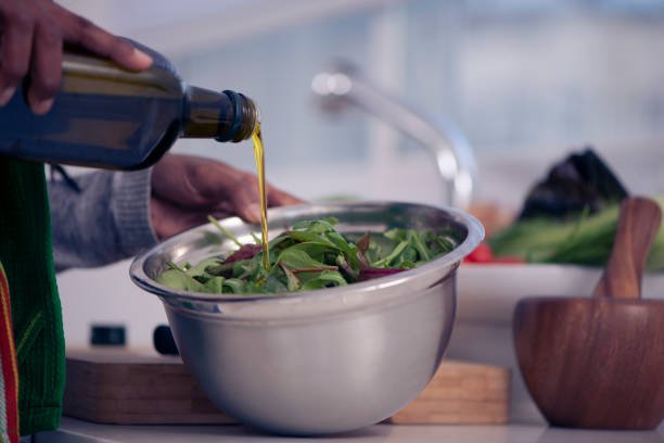 Seasoning green salad with olive oil. Close up image of woman's hand pouring olive oil to fresh mangold salad. olive oil pouring antioxidant liquid stock pictures, royalty-free photos & images