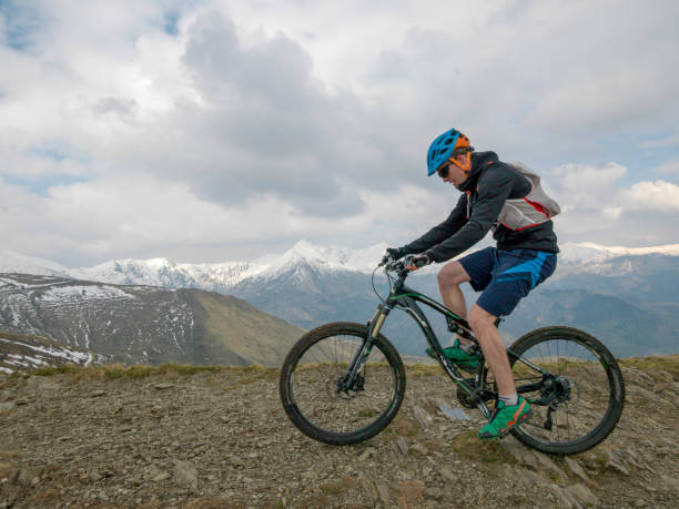 istock Mountain biker rides along snowy ridge line 1211664789