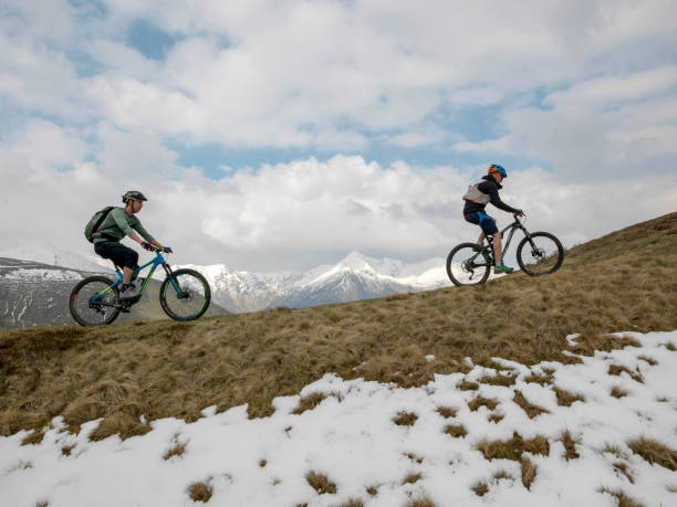 istock Mountain bikers ride up snowy ridge line 1211664796