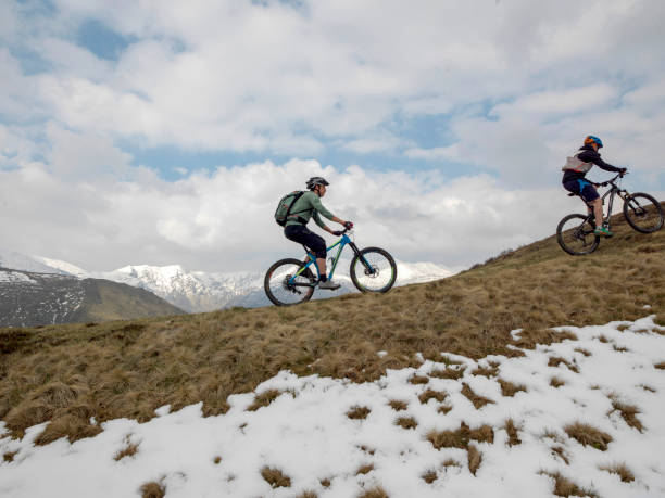 istock Mountain bikers ride up snowy ridge line 1211664806