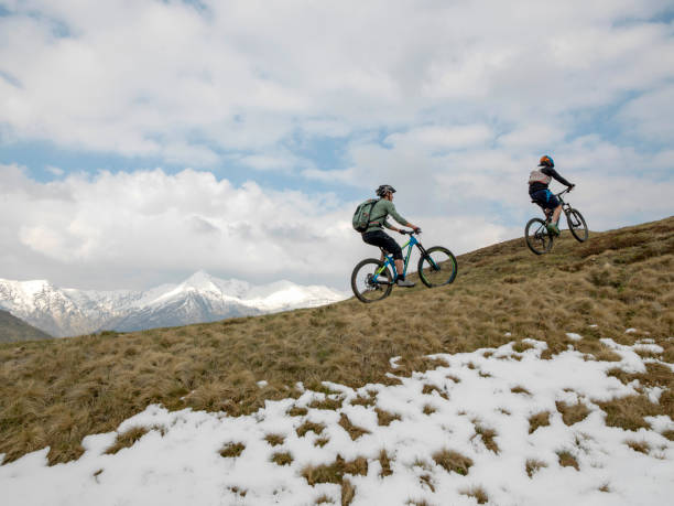 istock Mountain bikers ride up snowy ridge line 1211664810