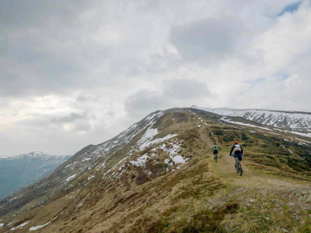 istock Mountain bikers ride up snowy ridge line 1211664854