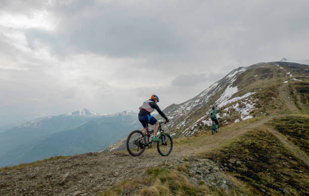 istock Mountain bikers ride up snowy ridge line 1211664927