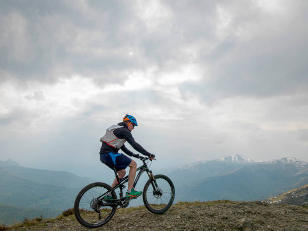 istock Mountain biker rides along snowy ridge line 1211664947