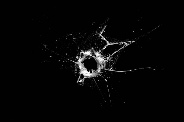 istock hole in the glass with cracks isolated on a black background 1211670611