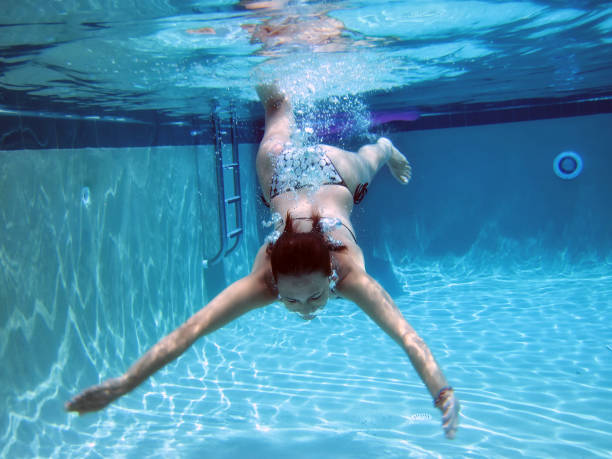 Synchronized swimming performance of a young woman practicing an act underwater in a swimming pool.