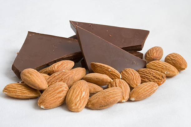 Almonds and dark chocolate pieces isolated on white Dark chocolate and almonds on a white background. Dark Chocolate and Almonds stock pictures, royalty-free photos & images