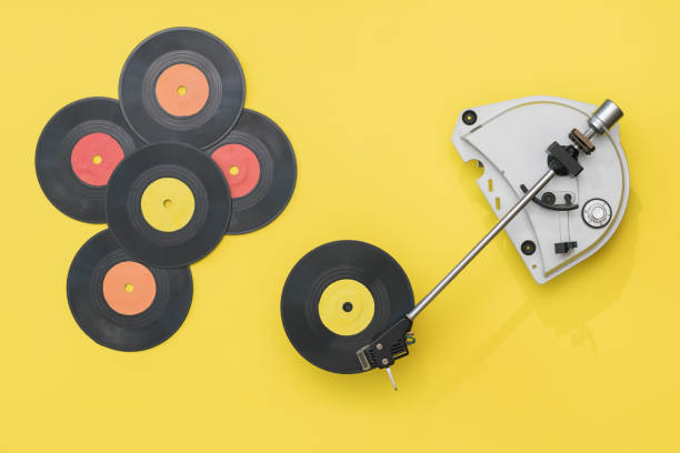 istock Vintage record player and multi-colored vinyl discs on a yellow background. 1211685528