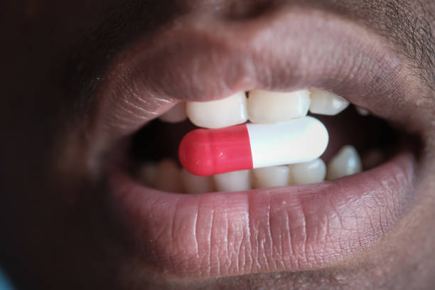 istock person mouth with pill or capsule , close up 1211689237