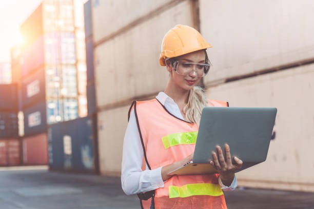 istock woman working with laptop in cargo container. Containers box from Cargo freight ship for import export 1211690091