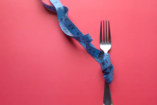 istock Diet and weight loss concept, fork and measuring tape 1211690146