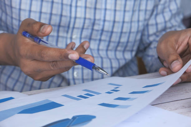 istock close up of person hand analyzing chart on office desk 1211690257
