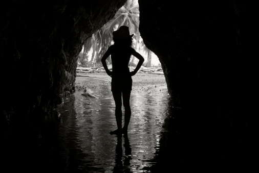 A young woman in a cowboy hat stands at the entrance to a cave on the Pacific coast of Costa Rica
