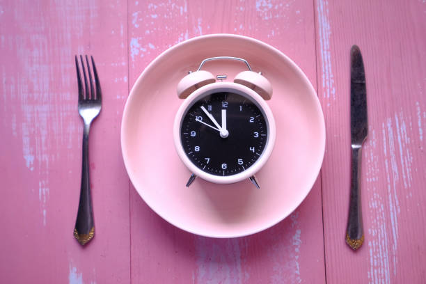 alarm clock on plate pink background alarm clock on plate pink background . fasting activity stock pictures, royalty-free photos & images