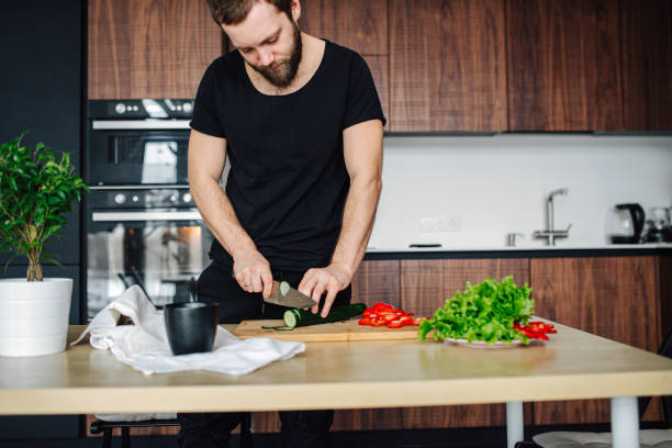 istock Man is slicing vegetables on a cutting board in the kitchen 1211699621