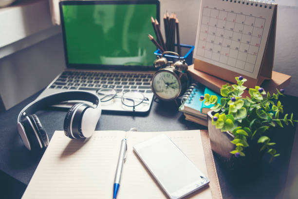 Diary and smartphone for planning work schedules and appointments.Desktop laptop headphone calendar clock diary books and old camera on wooden desk,Working space at home.Urban Lifestyle concept