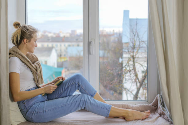 istock A girl with a book sits on a windowsill 1211706465