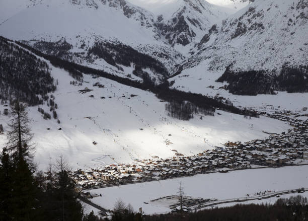 istock Snowy ski slope with cableways and town in mountain valley at winter evening 1211706608