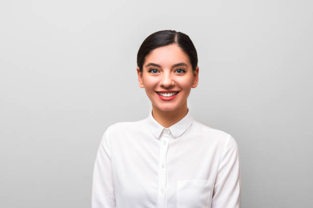 istock white collar worker young attractive brunette in white shirt with red lips, business makeup and hairs tied against grey background 1211708687
