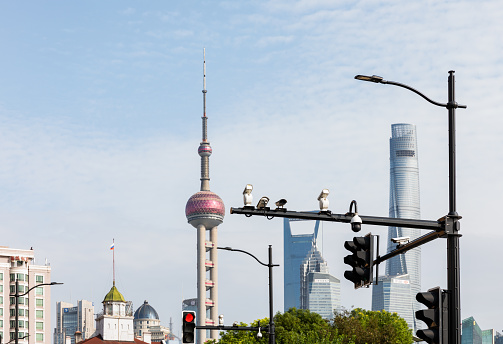 Shanghai, China - November 17, 2019: Massive surveillance cameras standing highly on tall traffic lamp post in Kongkou, Shanghai, with a background of skyscrapers at Lujiazui, Pudong.
