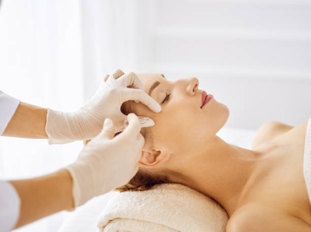 beautiful woman receiving beauty injections with closed eyes. beautician doctor hands doing beauty procedure to female face with syringe. cosmetic medicine and surgery concept - spa treatment beautiful healthcare and medicine white imagens e fotografias de stock