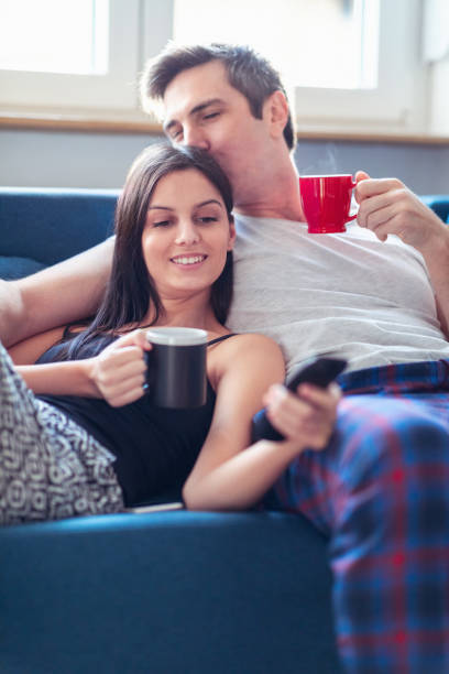 istock Kissing his girlfriend on the sofa on a cozy morning 1211716087