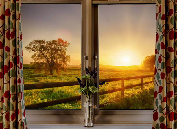Looking thought a window onto a beautiful rural sunrise across fields and fences in springtime