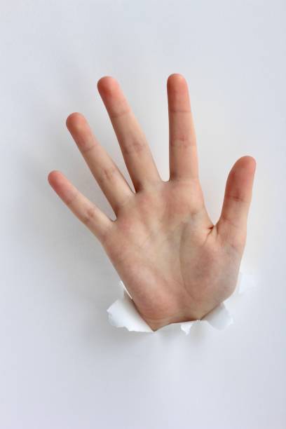 istock Hand showing stop gesture through a hole in paper. Gestures, signs and emotions. 1211729379