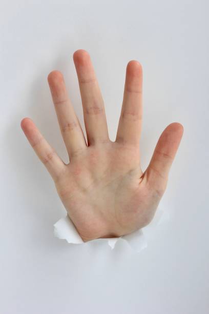 istock Hand showing stop gesture through a hole in paper. Gestures, signs and emotions. 1211729384