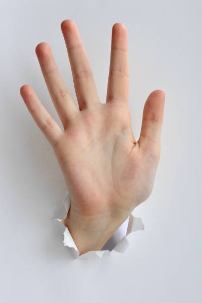 istock Hand showing stop gesture through a hole in paper. Gestures, signs and emotions. 1211729403