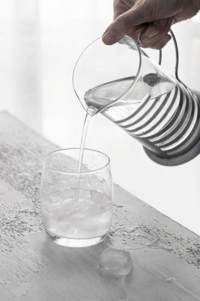 istock Clear cold water pouring into a glass with ice. Drinking water concept background 1211734595