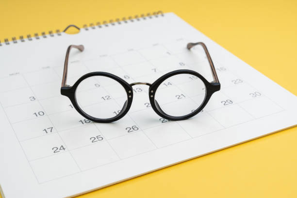 istock Eyeglasses on white clean calendar on yellow background using as thinking about plan, schedule or meeting apointment concept 1211739197