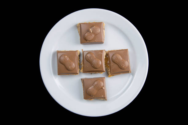 istock Five pieces of chocolate on a white plate isolated on a black background 1211739652