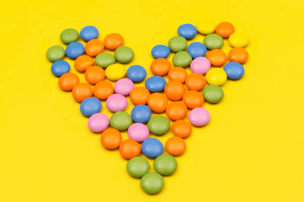 Colourful chocolate bean candies on yellow background