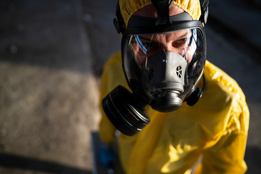 Portrait of a man in protective workwear examining radioactive ruined building.