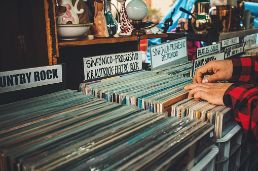 people selecting vinyl records on sale in a vintage market in Madrid, Spain.