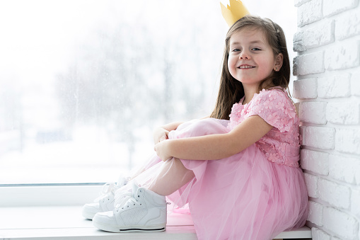 Cute little girl in a princess costume. Pretty child preparing for a costume party. Beautiful queen in gold crown