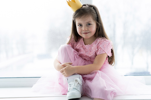 Cute little girl in a princess costume. Pretty child preparing for a costume party. Beautiful queen in gold crown