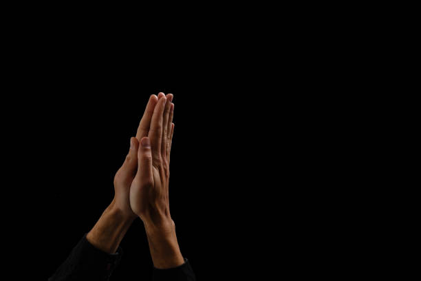 istock Handsome man sit prayer on black background. His hands are praying for God's blessings. 1211747122