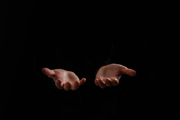 istock Handsome man sit prayer on black background. His hands are praying for God's blessings. 1211747207